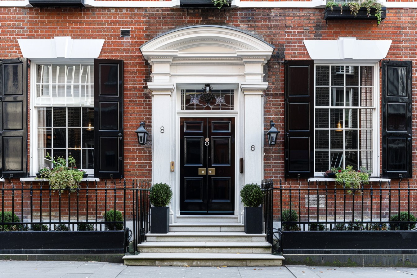 The exterior of a Georgian townhouse in central London, elegant symmetrical façade, red brick with white stone detailing, classic sash windows